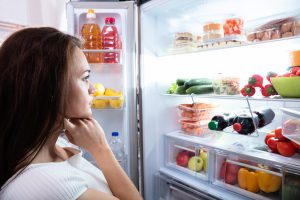 Vrouw met hongergevoel bij koelkast