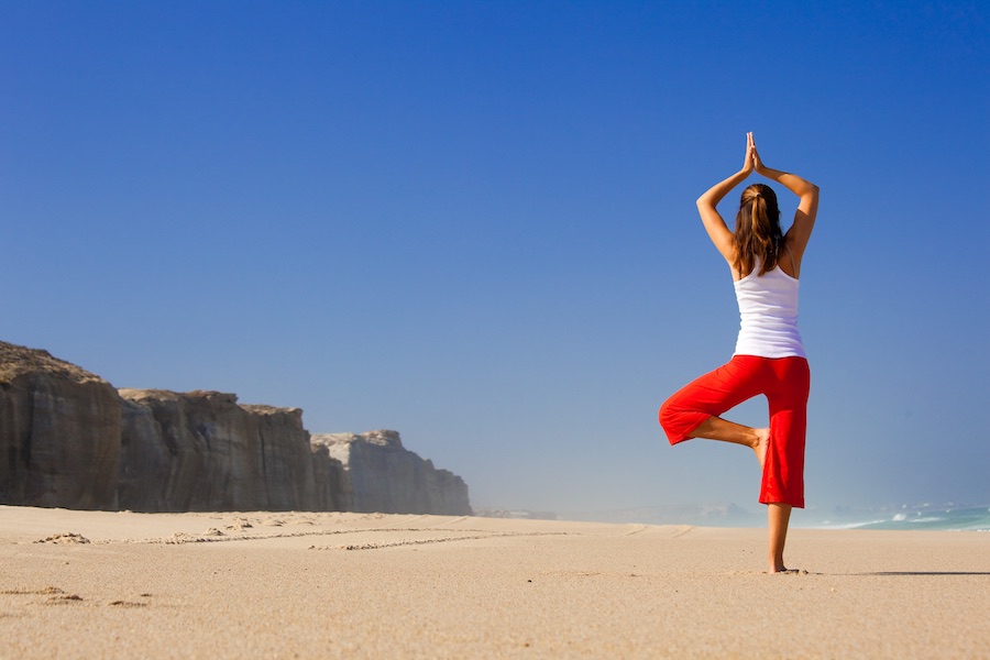 Mooie vrouw in yoga houding op het strand tips